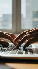 Focused Hands Typing on Laptop Keyboard in Bright Window Light.