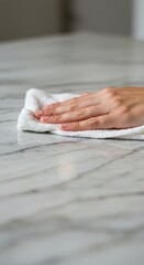 Hand Wiping Marble Surface with White Terry Cloth for Cleaning and Hygiene.