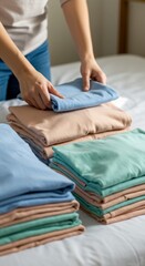 Neatly Folded Pastel TShirts on Bed Organized by Woman.