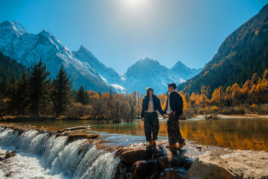 Bipenggou national park Young couple tourist with the Beautiful  snow mountains in autumn, Chengdu ,Sichuan in China.