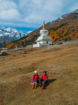 Aerial view of  Couple tourist relaxing  at  Mount Siguniang national park with the Beautiful  snow mountains in autumn, Chengdu ,Sichuan in China.