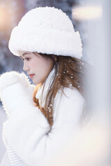 Young woman in winter attire with snow background.