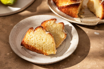 Two slices of Lemon bundt cake with lemon sugar glaze on a plate in bright morning light on beige backgrond