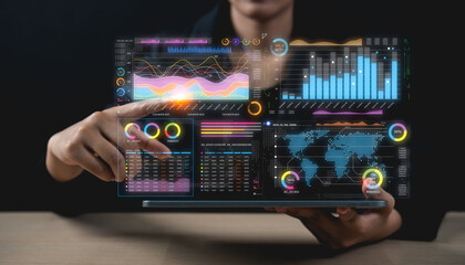 A person interacts with a transparent digital interface displaying colorful charts, graphs, and global data visualizations on a futuristic screen.