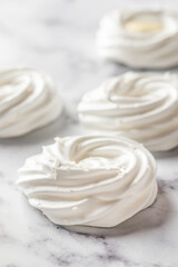 Meringues mini pavlova cakes close up on white marble background. Light summer dessert cooking