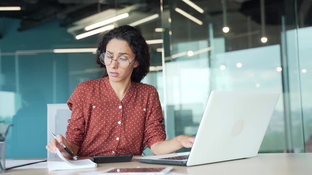 Disappointed young female employee having difficulty with task on computer while sitting at workplace in business office. Puzzled confused businesswoman cannot solve problems while working on project