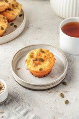 Savory zucchini muffin with cheese and seeds on a plate with tea on white kitchen table background. Healthy and quick morning breakfast