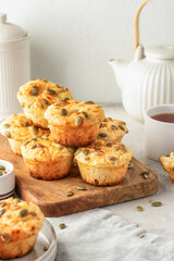 Savory zucchini muffins with cheese and seeds on wooden board on white kitchen table background....
