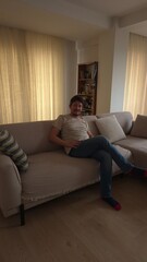 Obraz premium Young Man Relaxing at Home on a Cozy Sofa