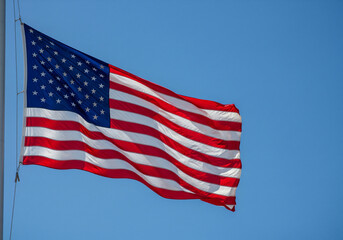 Obraz premium Vibrant American Flag Waving Against a Clear Blue Sky. Generative AI
