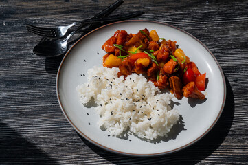 Pork in sweet and sour sauce with boiled rice on a plate. 