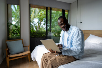 African american black man working on a laptop in a tropical-inspired home office