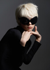 Stylish young woman with short blonde hair wearing oversized black sunglasses, posing elegantly...