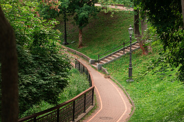 park landscaped environment space grass hills paved track and stairs in trees surrounding green leaves