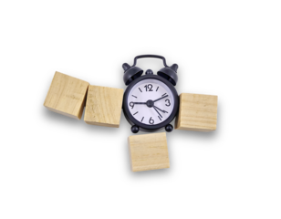 A black alarm clock surrounded by wooden blocks, suggesting time management or deadlines.