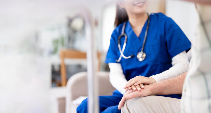 Female doctor reassuring older man in modern clinic, holding hands with patient for help.