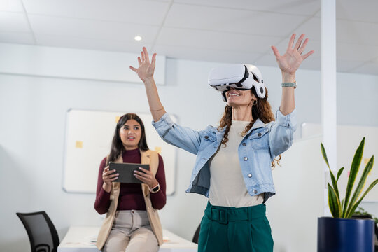 Diverse coworkers testing VR headset and tablet at office desk whiteboard notes plant, copy space - Powered by Adobe