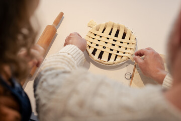 Senior man and woman weaving lattice over pie dish on kitchen countertop with rolling pin