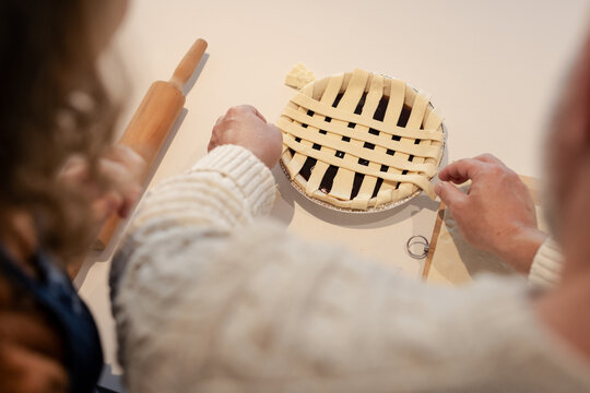 Senior man and woman weaving lattice over pie dish on kitchen countertop with rolling pin - Powered by Adobe