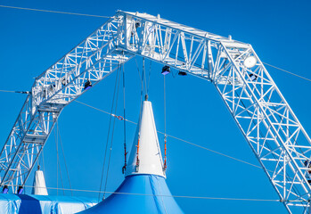 Bright blue circus tent raised in a bustling outdoor location, preparing for exciting performances and attractions in the warm afternoon sun