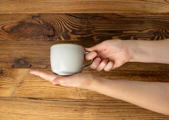 Hand Holds Cup, Empty Cup in Hands, Coffee Mug, Teacup Mockup, Cup in Arms on Wooden Table