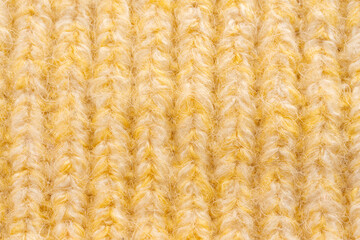 Knitted woolen fabric pattern in pale yellow. Macro texture of a sweater