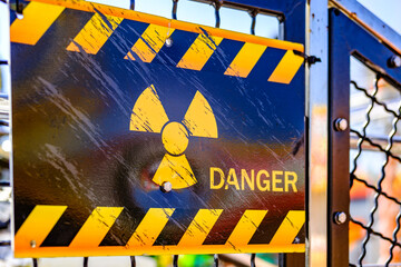 Warning sign indicates radiation hazard at industrial facility with caution stripes in midday...