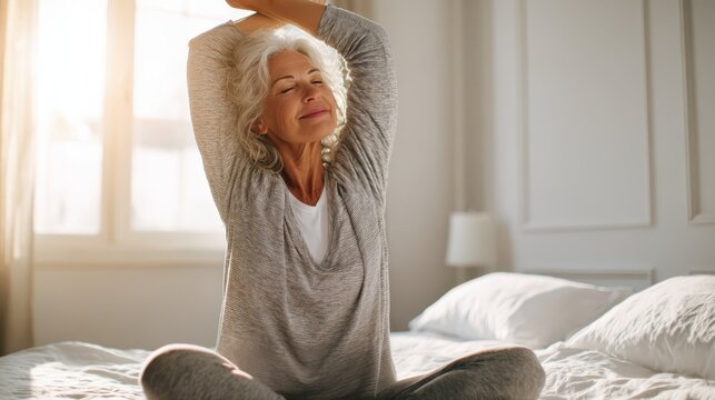 Senior woman relaxing, gently stretching in comfortable bed, practicing mindful morning wellness routine with peaceful bedroom backdrop