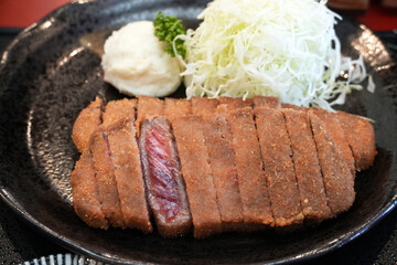 A close-up of mouthwatering Japanese beef katsu with cabbage and potato salad, ready to eat.