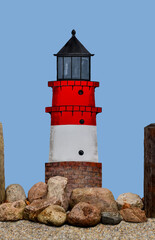 Ein Leuchtturm, Steine und spritzendes Wasser.
