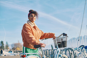 Outdoor fashion portrait of pretty african woman walking with bicycle