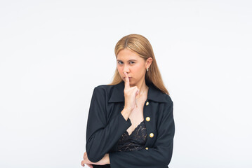 A strict young Asian woman staring intently with a finger on her mouth in a firm shushing gesture....
