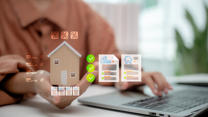 Hand holding model house with digital mortgage documents and interest rates. Concept of real estate, home loan approval, property investment, financial planning, and housing finance.