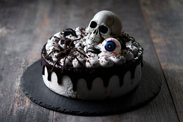 Spooky Halloween chocolate Cake with Skull, Eyeball, and Spider Decoration on dark background