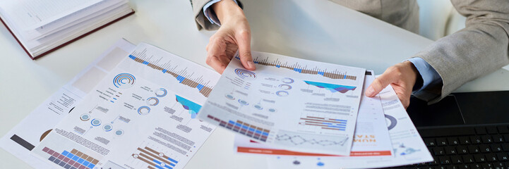 Businesswoman analyzing reports and charts at office desk