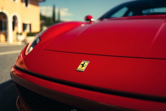 close-up of ferrari emblem on red sports car by the coast

