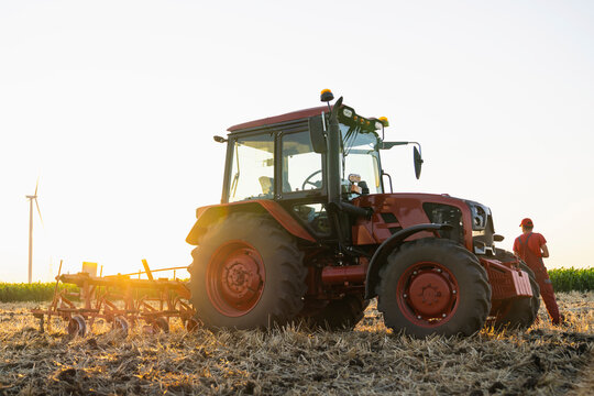 Farmer with tractor and wind turbine in field illustrating sustainable agriculture
