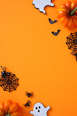Halloween flat lay with pumpkins, ghosts, bats, spider webs and spiders on vibrant orange backdrop