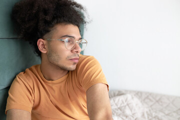 Serious depressed man sitting in bed with procrastination and apathy and indifference, feeling...