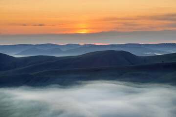 Sunrise over a mountain valley, with floating clouds