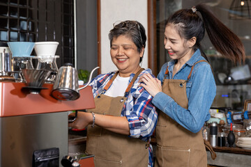 Two female baristas smiling and working together at the espresso machine, showing teamwork,...