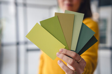 Hand holding color swatches in creative loft workspace
