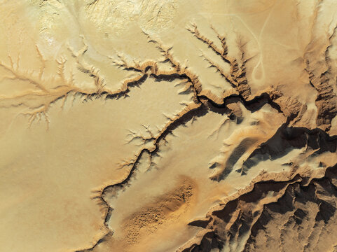 Aerial view of the arid landscape, where deep shadows carve intricate patterns into the sun-baked earth, Tsondab Valley, Khomas, Namibia.