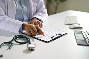 Close up of doctor reviewing patient information on a clipboard. Healthcare concept