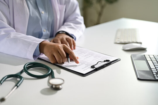 Close up of doctor reviewing patient information on a clipboard. Healthcare concept