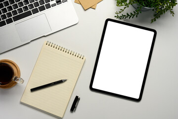 Flat lay of workspace featuring digital tablet with empty screen, laptop, notebook and coffee cup