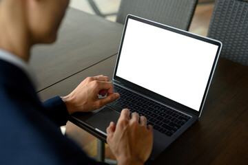Close up of businessman using laptop with white display in modern office