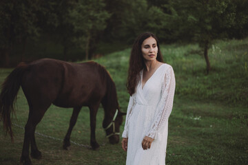Beautiful model in white dress near horse