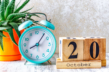 Wooden calendar with the date October 20.Monthly calendar for planning and management concept with alarm clock on wooden background