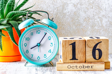 Wooden calendar with the date October 16.Monthly calendar for planning and management concept with alarm clock on wooden background